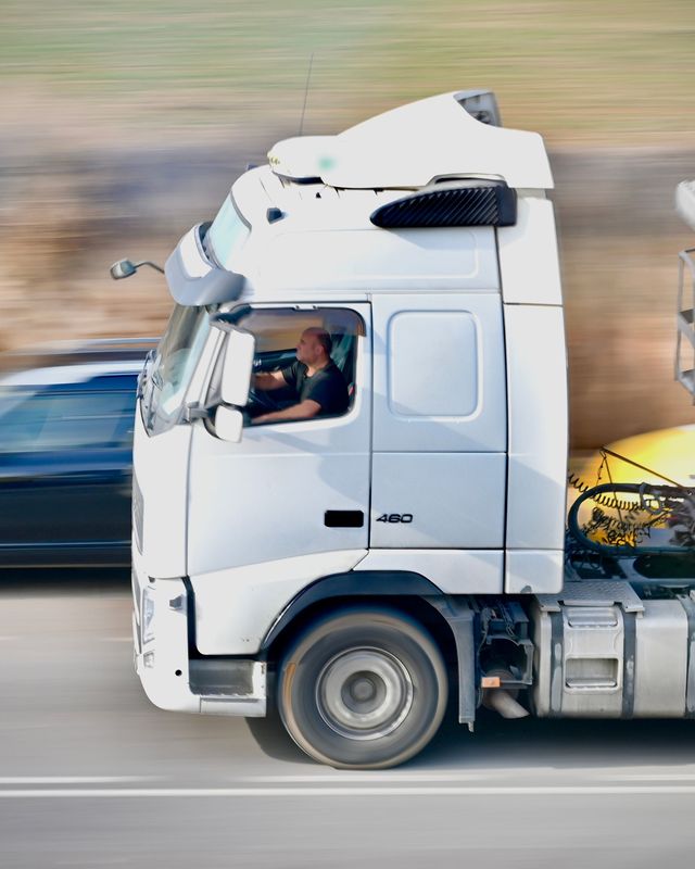 Een chauffeur aan het stuur van een witte trekker